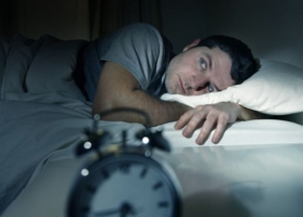 Man laying awake in bed unable to sleep