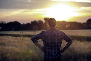 Man surveying a field at sunrise