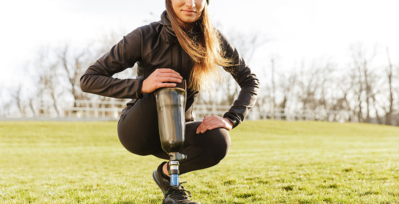 Woman in field gesturing to her prosthetic leg
