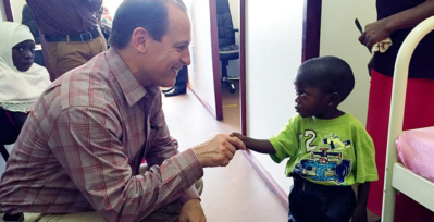 Image of Russell E. Ware M.D., Ph.D., shaking hands with a young sickle cell patient in Africa.