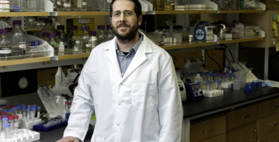 Headshot of researcher Jason McLellan, Ph.D. in lab coat in front of science equipment